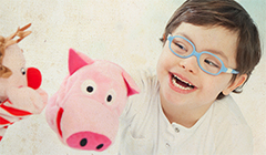 Child with blue glasses and hand puppets